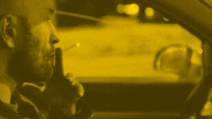 Zdjęcie: Łysy mężczyzna z krótkim zarostem pali papierosa podczas kierowania samochodem. Widok z perspektywy pasażera.